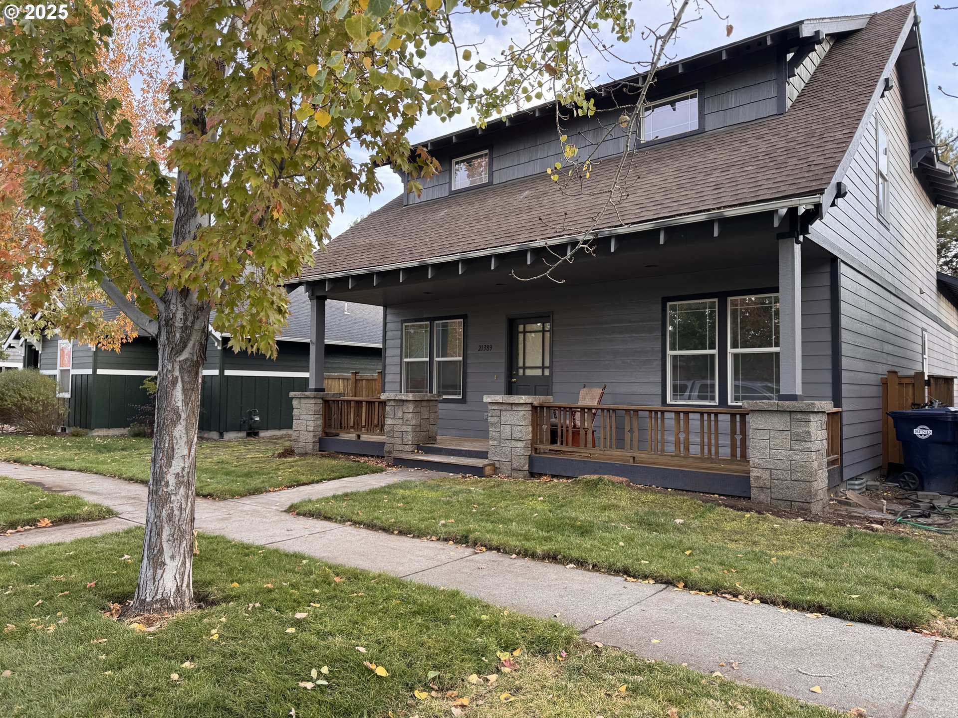 a front view of a house with a yard and large tree