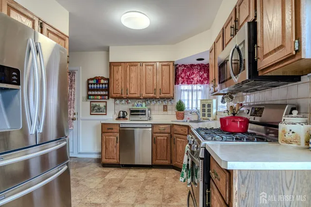 a kitchen with stainless steel appliances granite countertop a stove a sink dishwasher a refrigerator and a microwave