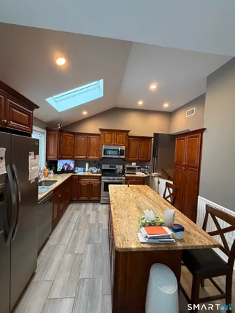 a kitchen with stainless steel appliances kitchen island granite countertop a table chairs and a refrigerator
