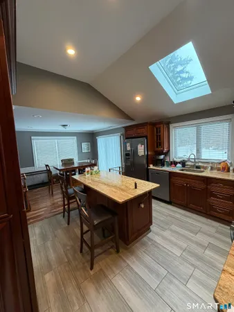 a room with stainless steel appliances kitchen island granite countertop a table chairs and a refrigerator