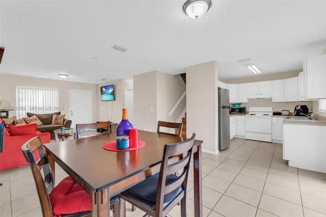 a kitchen with stainless steel appliances granite countertop a dining table chairs and white cabinets