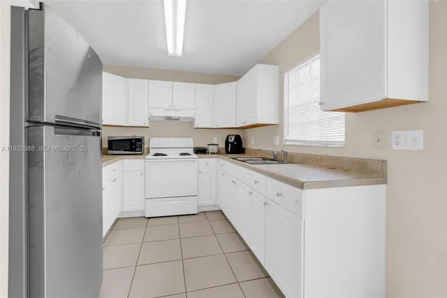 a kitchen with white cabinets appliances and a window