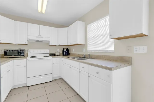 a kitchen with cabinets appliances a sink and a window