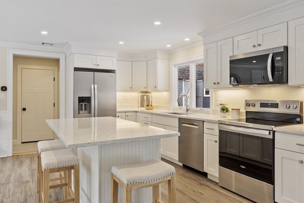 4 Richard Road Hudson, MA 01749 - Photo 6 of 40 a kitchen with stainless steel appliances granite countertop a stove a sink a microwave a refrigerator and white cabinets with wooden floor