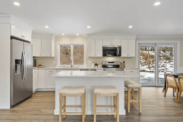 a kitchen with stainless steel appliances granite countertop a stove top oven a refrigerator a sink and a dining table with wooden floor