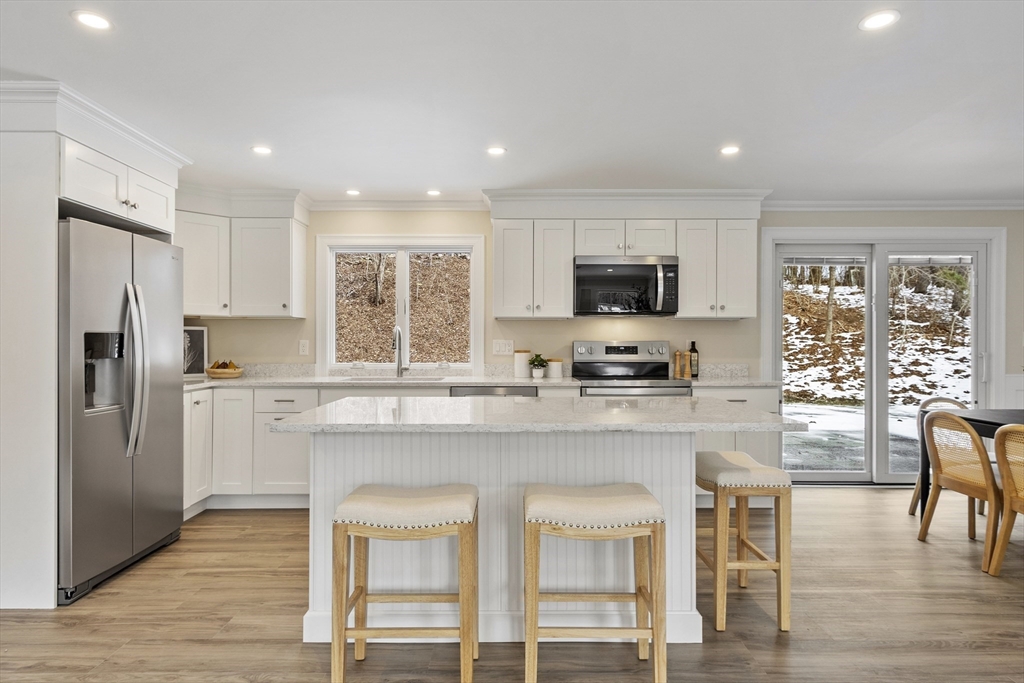 4 Richard Road Hudson, MA 01749 - Photo 8 of 40 a kitchen with stainless steel appliances granite countertop a stove top oven a refrigerator a sink and a dining table with wooden floor