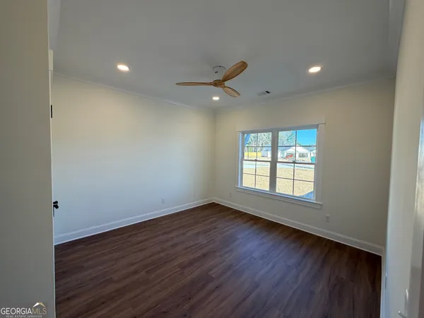 an empty room with wooden floor and windows