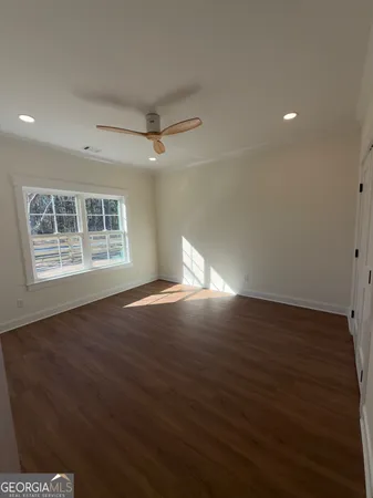 a view of an empty room with wooden floor and a window