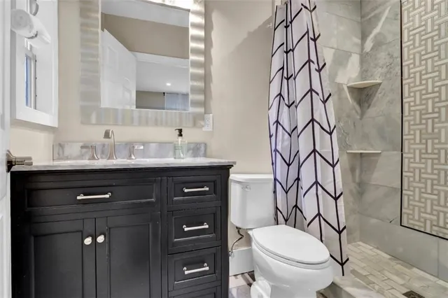 a bathroom with a granite countertop sink toilet and shower