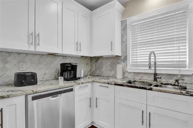 a kitchen with stainless steel appliances granite countertop a sink a stove and a white cabinets
