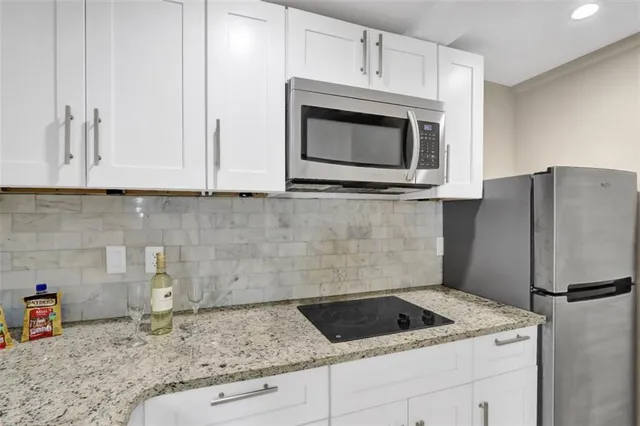 a kitchen with granite countertop white cabinets and refrigerator