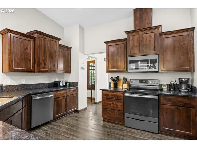 a kitchen with stainless steel appliances granite countertop a stove top oven a sink dishwasher and wooden cabinets