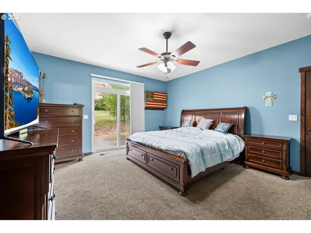 a bedroom with a bed dresser and a flat tv screen