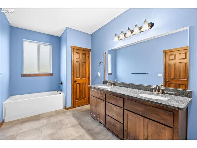 a bathroom with a sink double vanity granite tub mirror and vanity