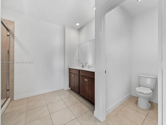 a spacious bathroom with a granite countertop sink a toilet and a mirror
