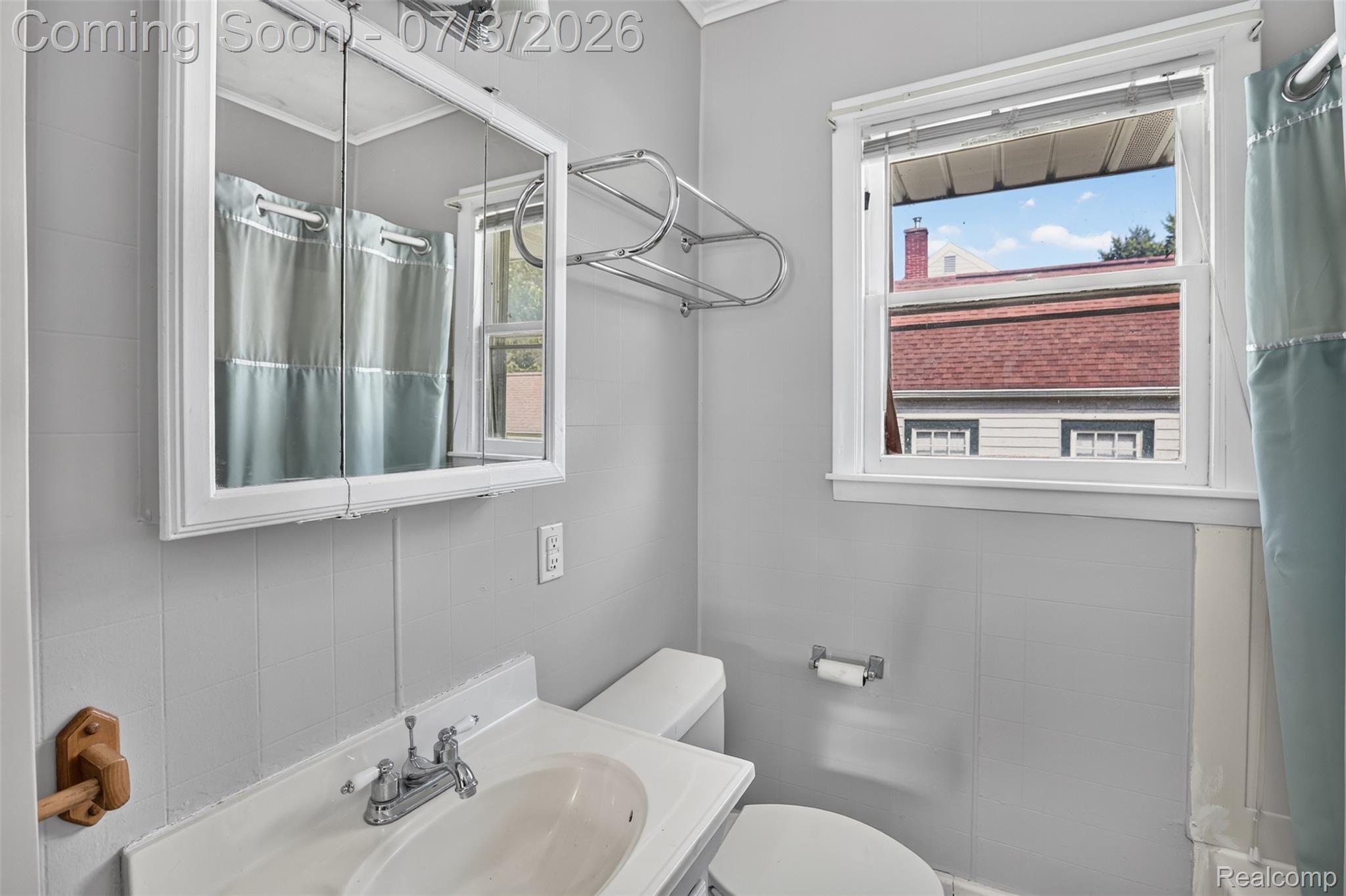 4322 Baker Road Bridgeport, MI 48722 - Photo 15 of 29 Bathroom featuring light gray paneled walls, a white vanity with an integrated sink, a mirrored medicine cabinet, and a double-hung window