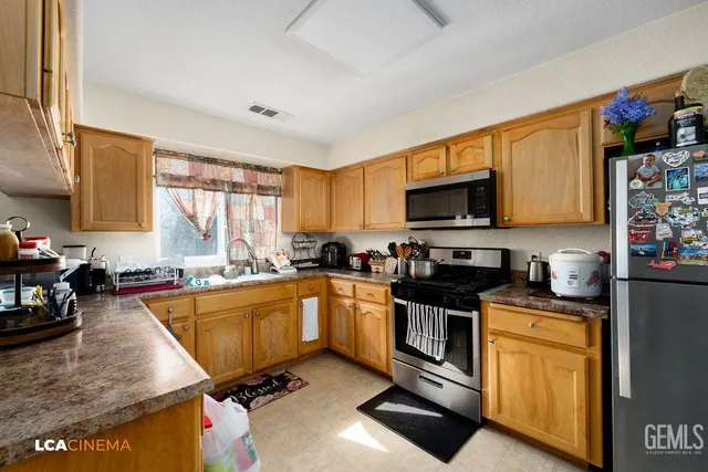 a kitchen with stainless steel appliances granite countertop a stove top oven a sink dishwasher a dining table and chairs with wooden floor