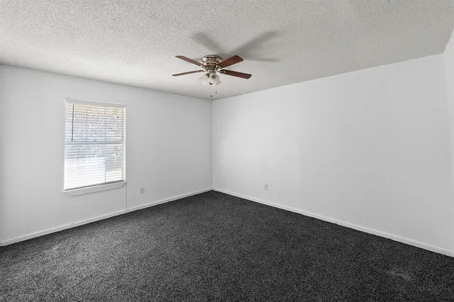 an empty room with a window and a fan