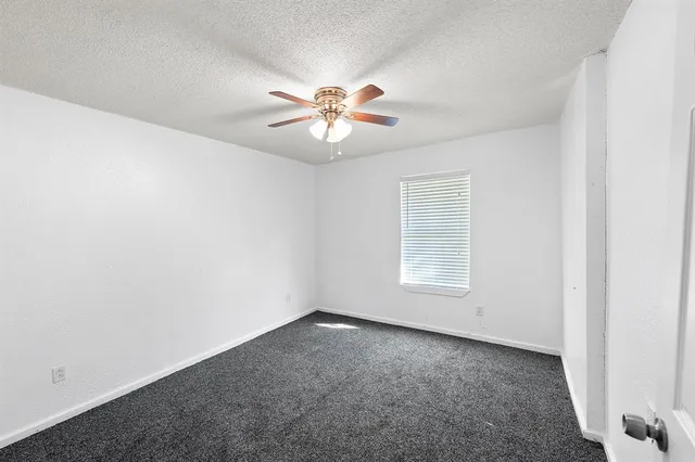an empty room with a window and a ceiling fan