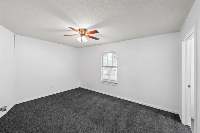 an empty room with windows and chandelier fan