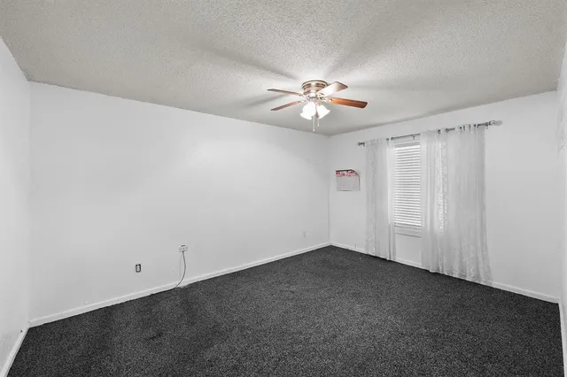 an empty room with a fan & a window