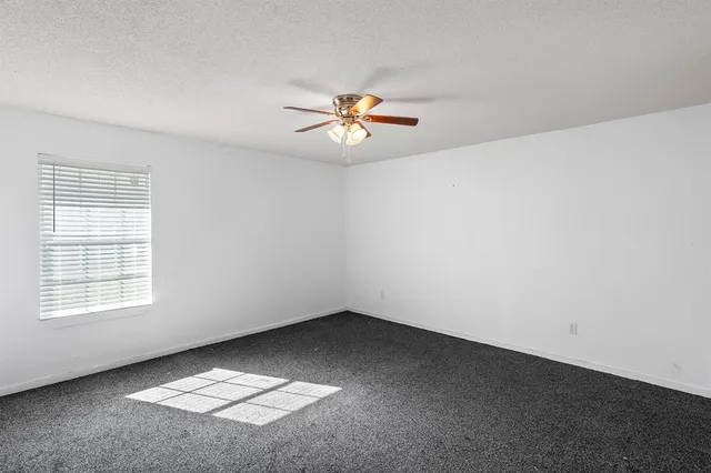 an empty room with a window and a ceiling fan