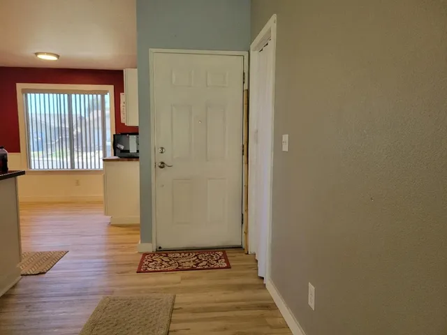 a view of a hallway with wooden floor and a bathroom
