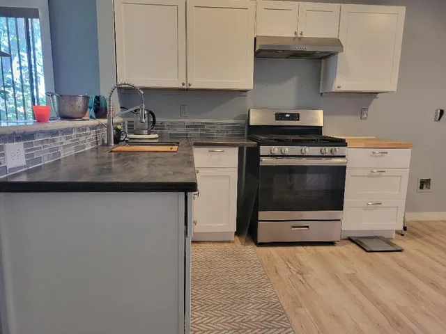 a kitchen with stainless steel appliances granite countertop a stove a sink and a microwave