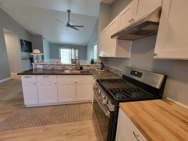 a kitchen with stainless steel appliances granite countertop a stove a sink dishwasher and cabinets with wooden floor