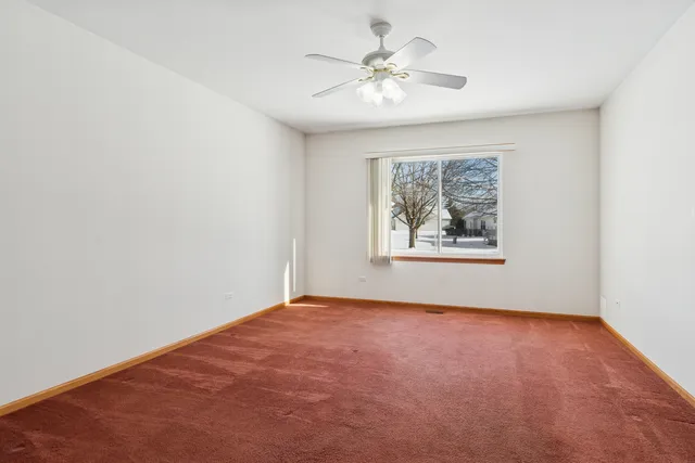 an empty room with windows and chandelier fan