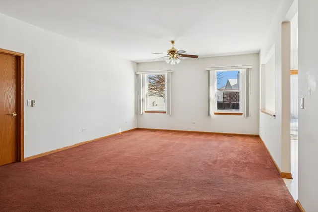 an empty room with windows and ceiling fan