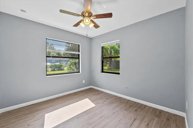 a view of an empty room with a window and wooden floor