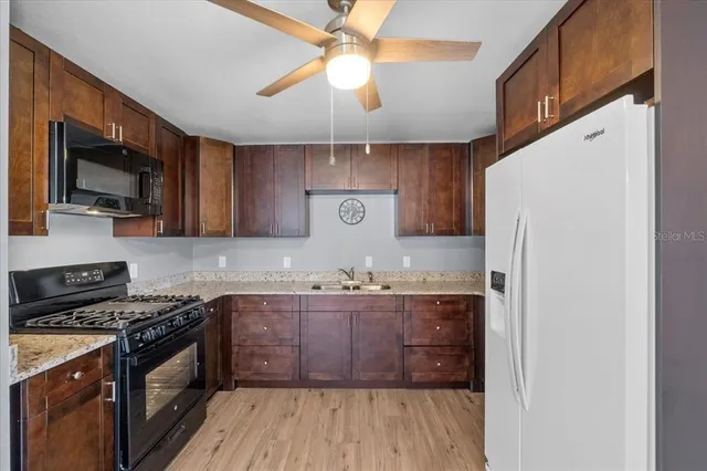 a kitchen with stainless steel appliances granite countertop wooden cabinets a stove a sink and a refrigerator