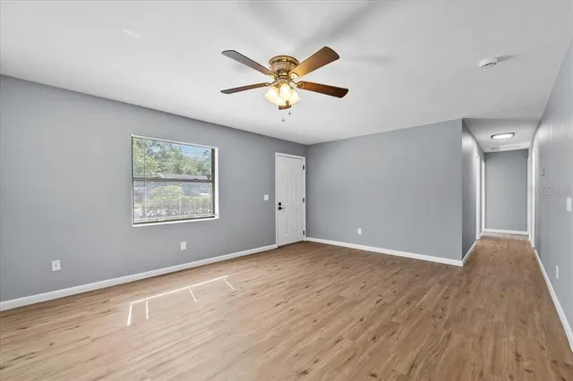 a view of an empty room with window and wooden floor