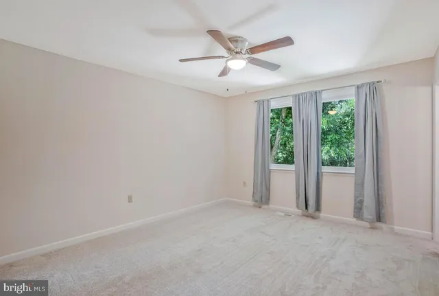 an empty room with a ceiling fan and windows