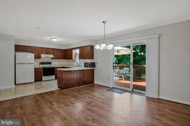 a large kitchen with stainless steel appliances granite countertop a refrigerator a oven a island and a wooden floor