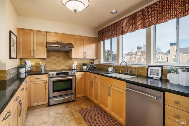 a kitchen with stainless steel appliances granite countertop a stove a sink and a microwave