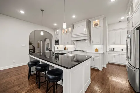 a kitchen with stainless steel appliances granite countertop a sink a stove and a wooden floors