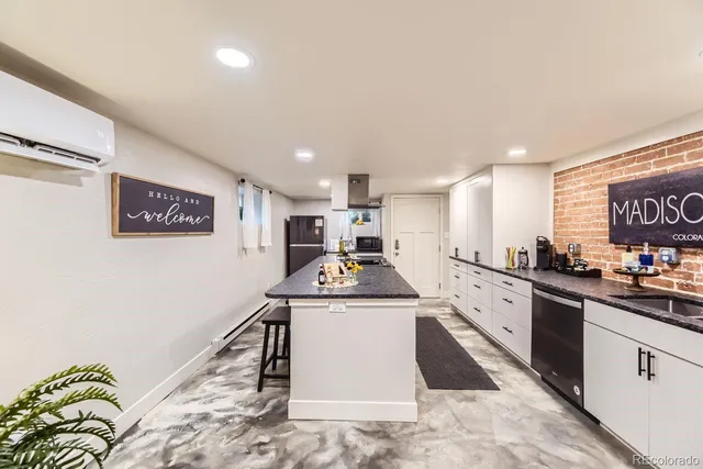 a kitchen with stainless steel appliances granite countertop a stove a sink a refrigerator white cabinets and wooden floor