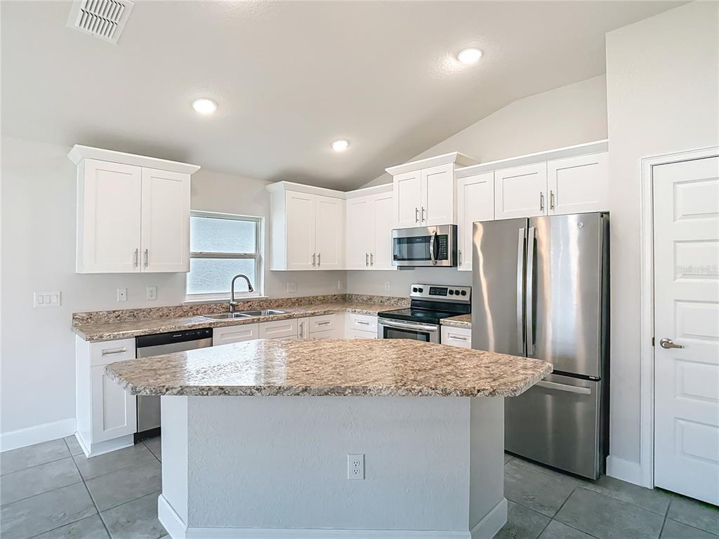 14917 Tropical Violet Way Wimauma, FL 33598 - Photo 15 of 77 a kitchen with stainless steel appliances granite countertop a refrigerator sink stove microwave and cabinets