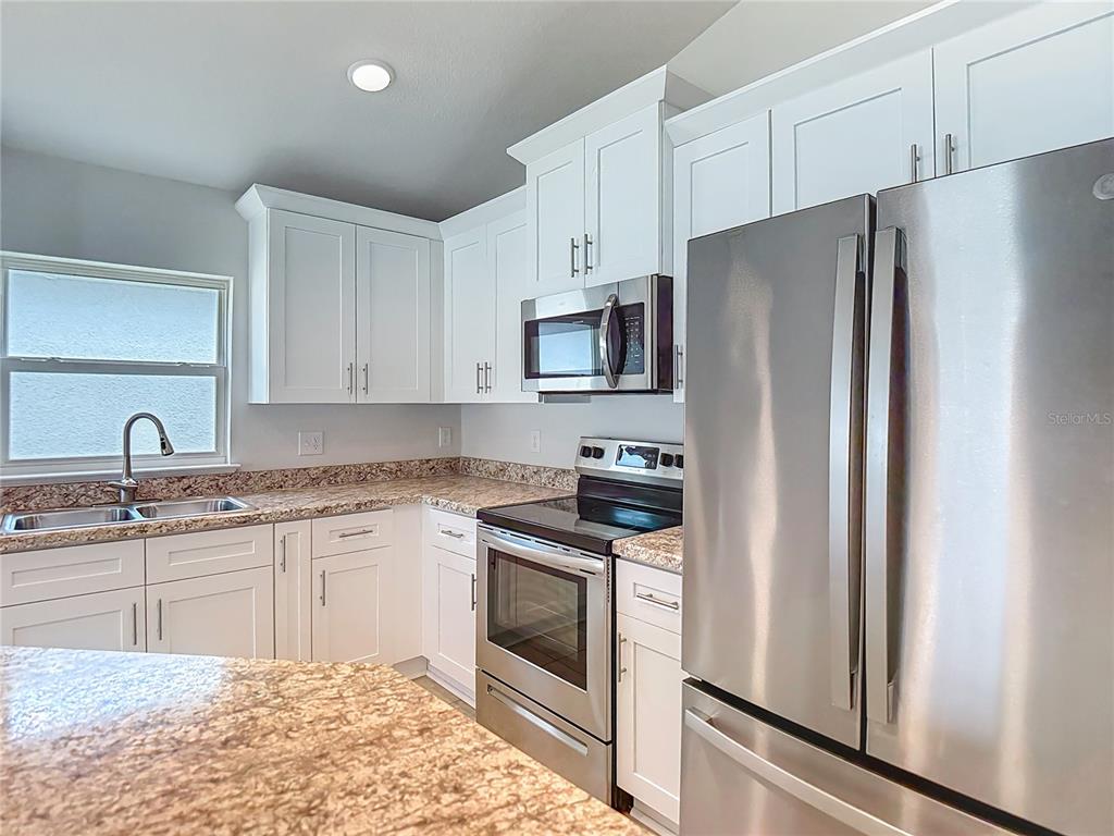 14917 Tropical Violet Way Wimauma, FL 33598 - Photo 16 of 77 a kitchen with stainless steel appliances granite countertop a refrigerator sink and stove