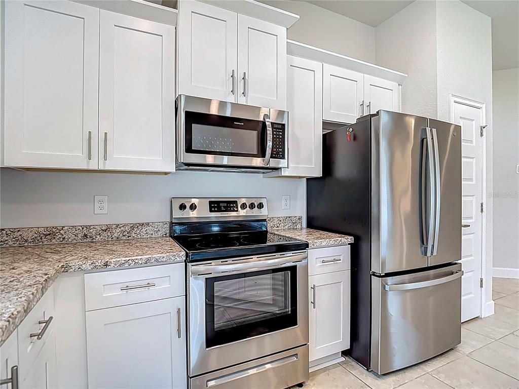 14917 Tropical Violet Way Wimauma, FL 33598 - Photo 19 of 77 a kitchen with white cabinets and stainless steel appliances