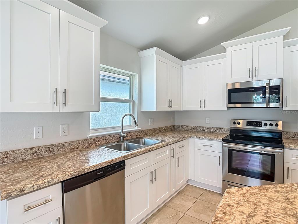 14917 Tropical Violet Way Wimauma, FL 33598 - Photo 20 of 77 a kitchen with granite countertop white cabinets and white appliances
