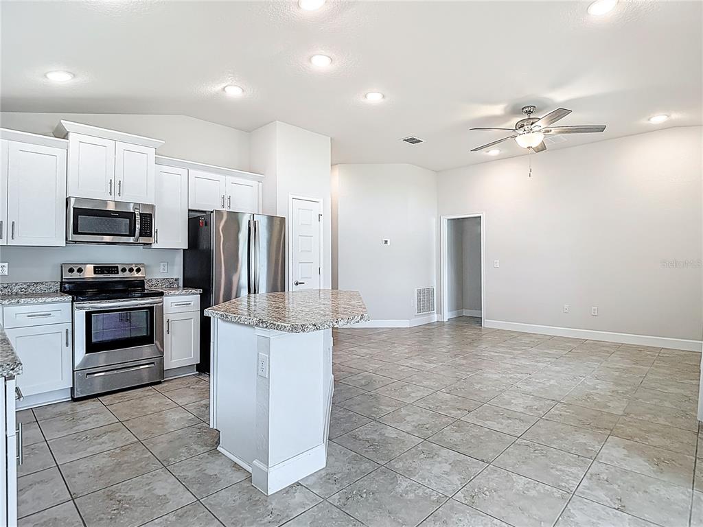 14917 Tropical Violet Way Wimauma, FL 33598 - Photo 21 of 77 a kitchen with kitchen island a counter top space appliances and cabinets