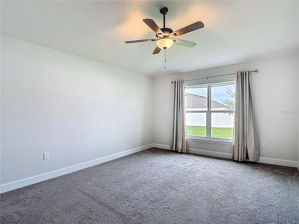 14917 Tropical Violet Way Wimauma, FL 33598 - Photo 26 of 77 an empty room with chandelier fan and windows
