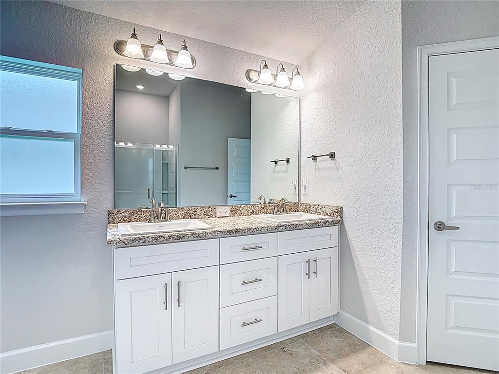 14917 Tropical Violet Way Wimauma, FL 33598 - Photo 32 of 77 a bathroom with a granite countertop double vanity sink and a mirror