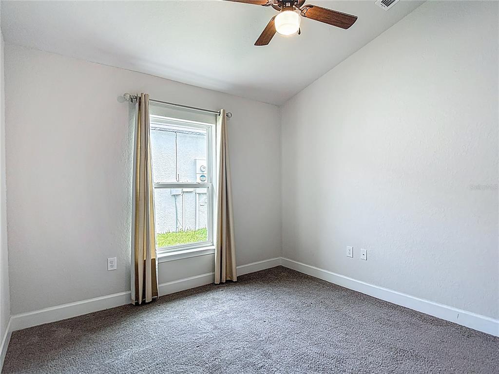 14917 Tropical Violet Way Wimauma, FL 33598 - Photo 46 of 77 an empty room with a ceiling fan and windows