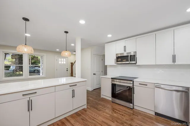 a kitchen with stainless steel appliances granite countertop a sink a stove a refrigerator and white cabinets