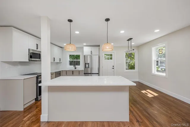a large kitchen with kitchen island a stove a sink a center island and wooden floor