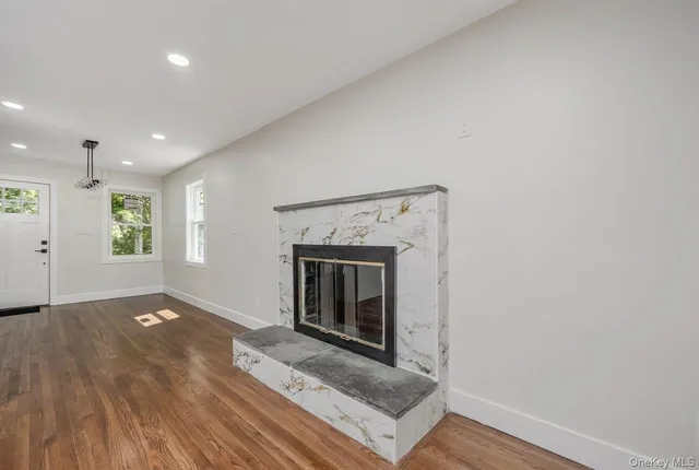 an empty room with wooden floor a fireplace and windows